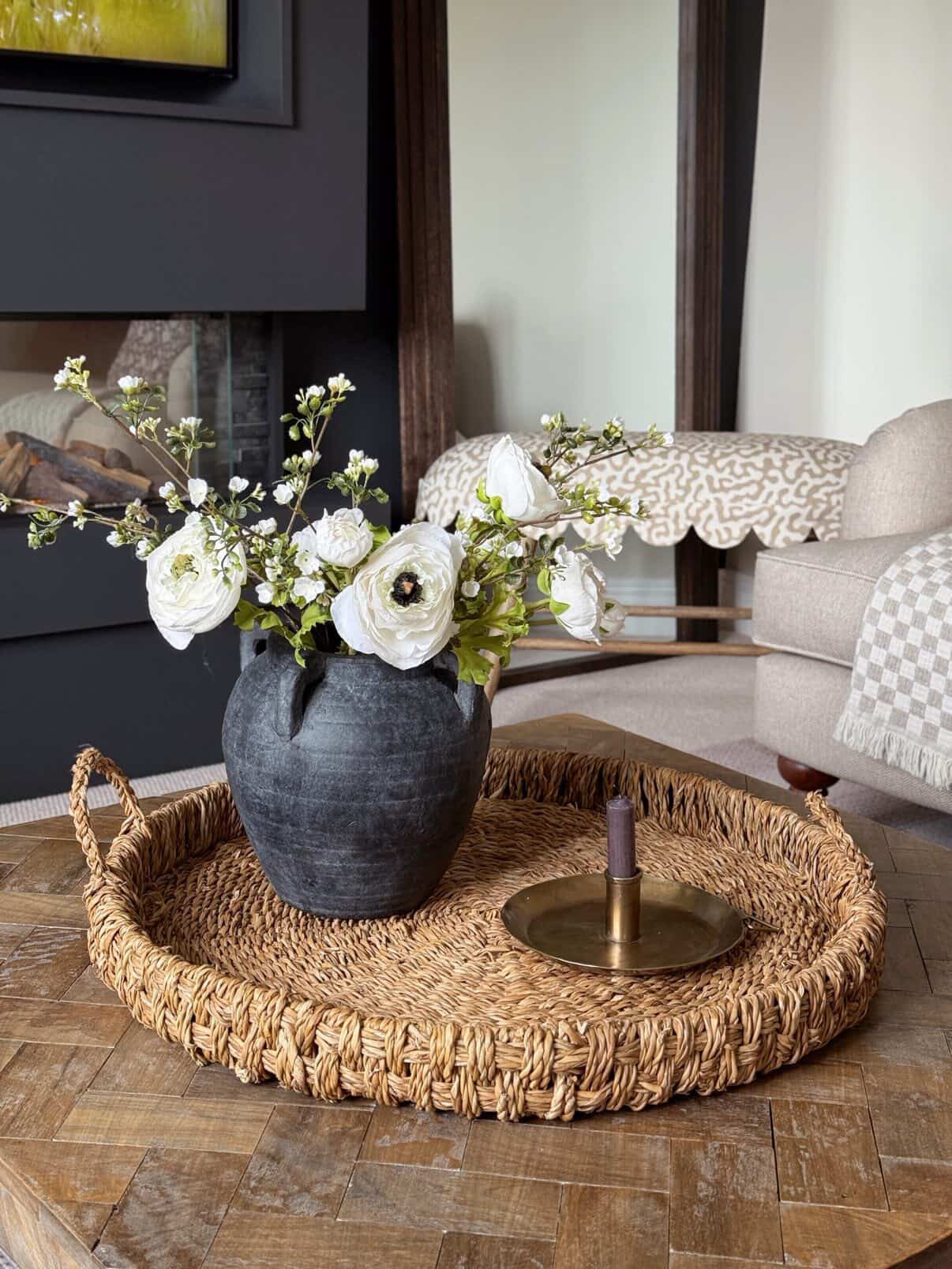 Decorative vase with flowers on a woven tray in a living room setting