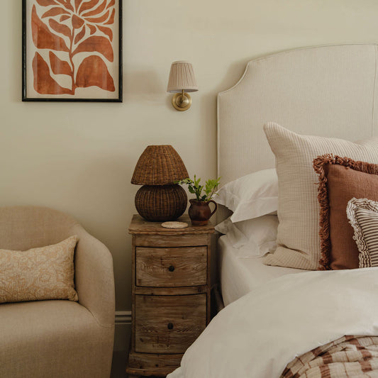 Cozy bedroom with a bed, armchair, and nightstand with lamp.