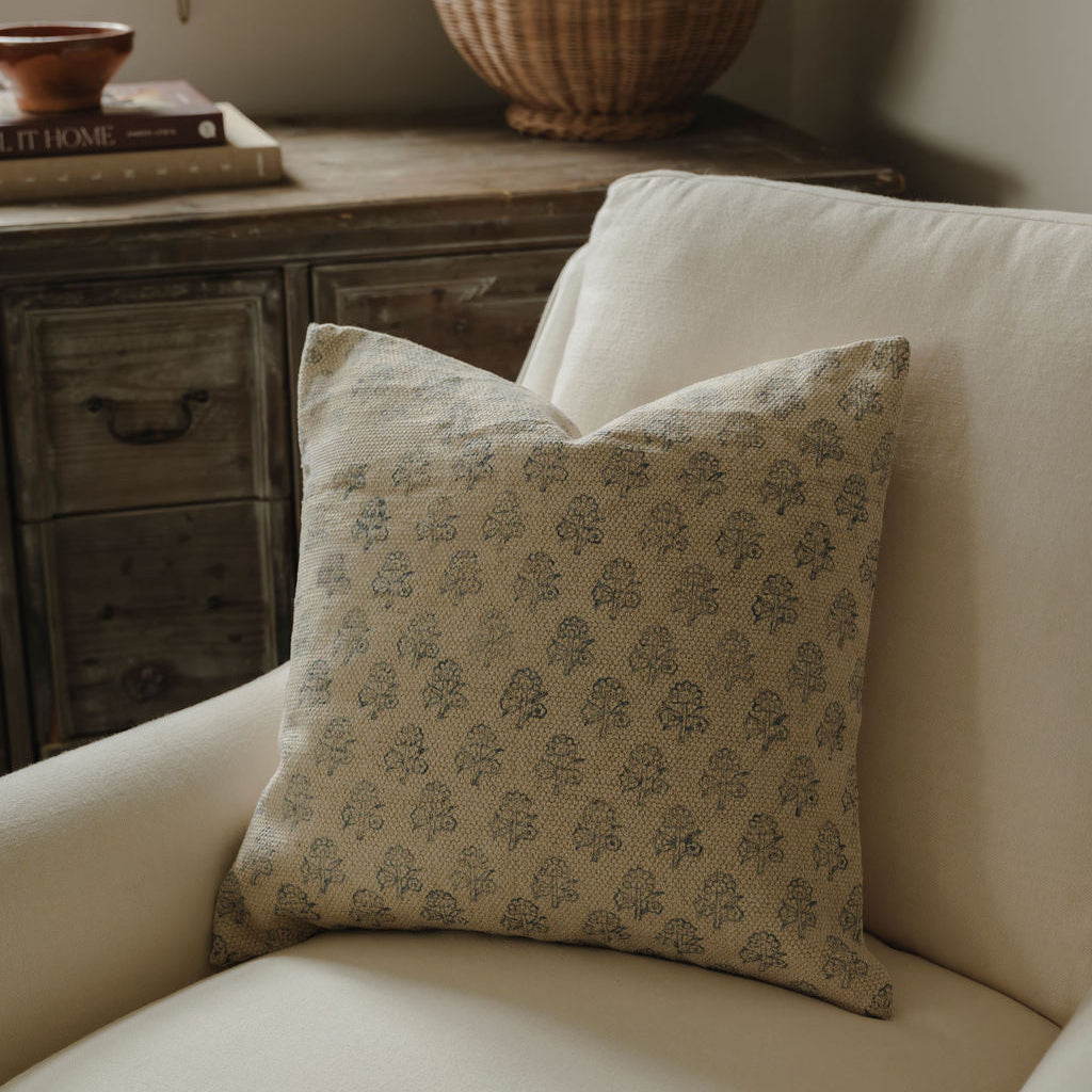 Decorative pillow on a beige sofa with a wooden side table and wicker basket in the background.