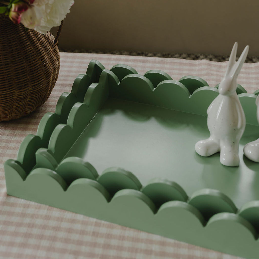 Green scalloped-edge tray with a white rabbit figurine on a checkered tablecloth.
