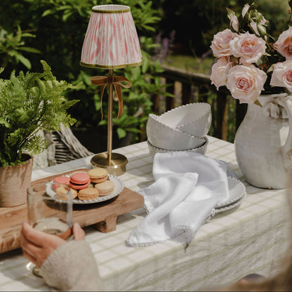 Outdoor setting with a table featuring a lamp, macarons, and flowers.